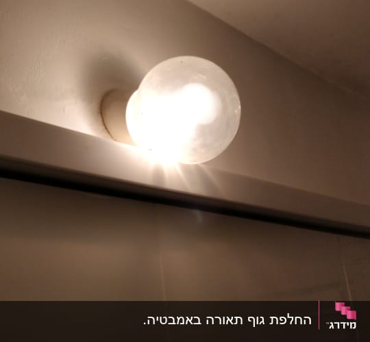 נורה עגולה דולקת על קיר לבן